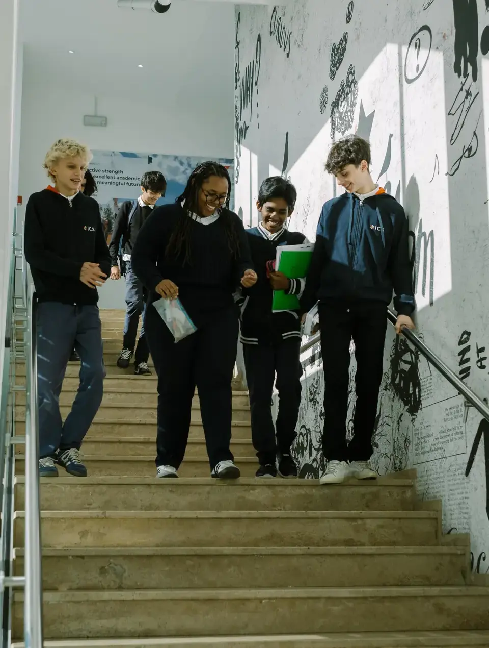 students walking down a staircase together laughing between classes