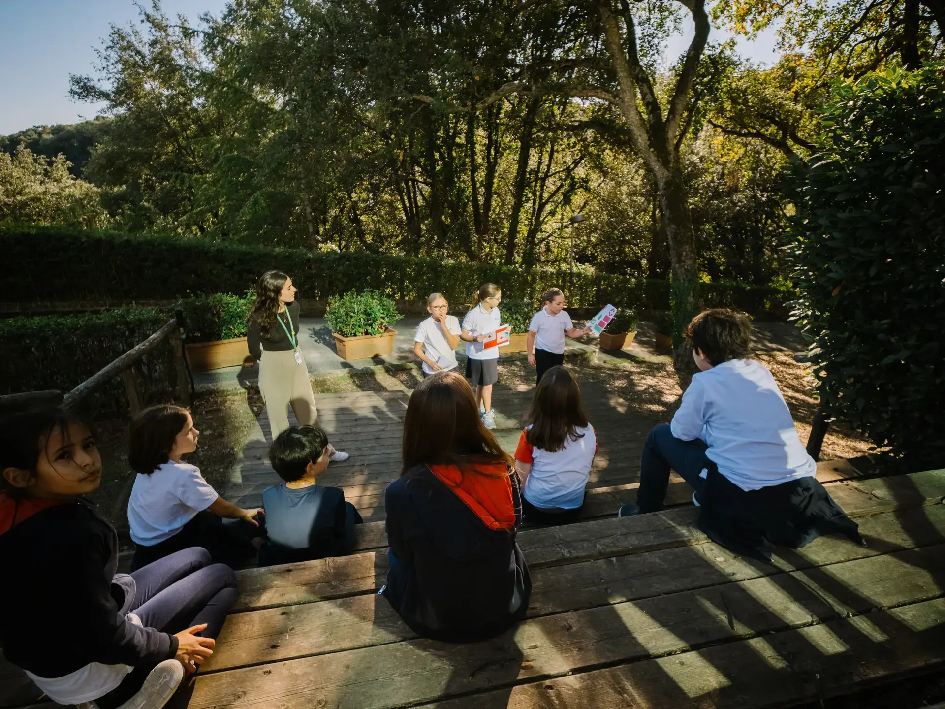 students presenting to classmates on a wooden deck during an outdoor lesson