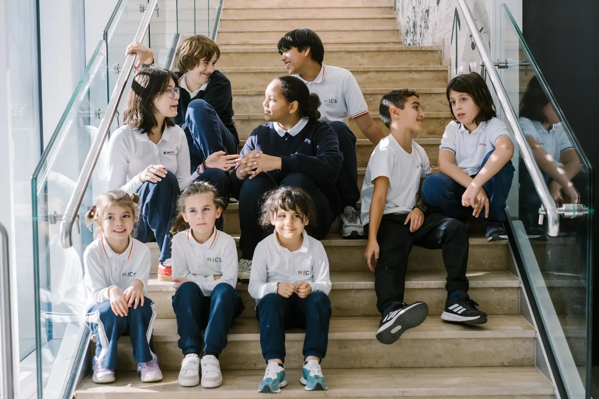 students in school uniforms sitting together on a staircase talking and smiling