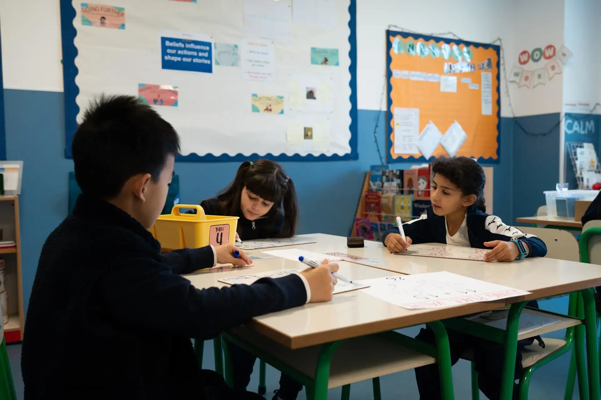 students writing on whiteboards at their desks in the classroom.