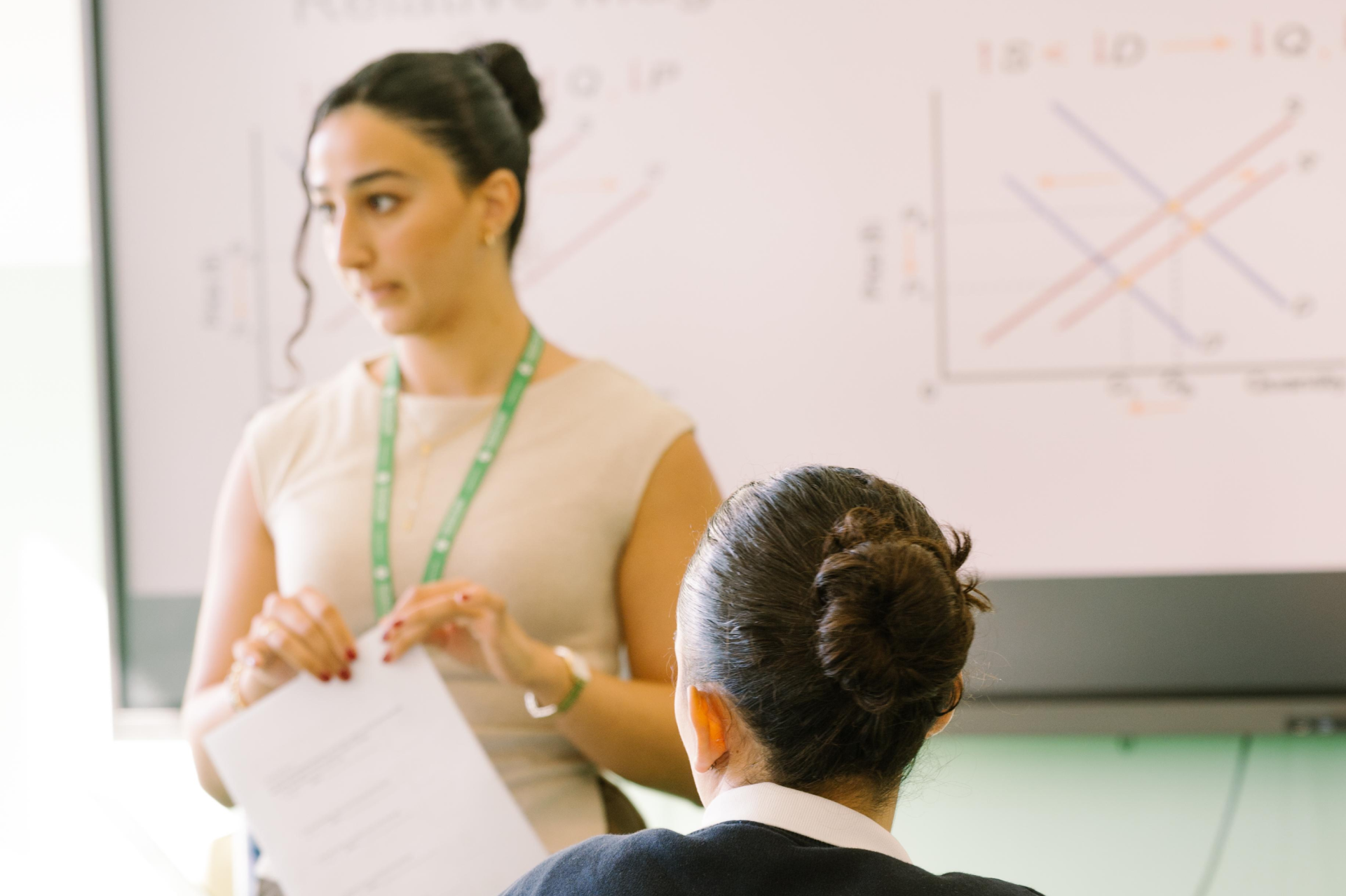 teacher speaking with a student in front of a whiteboard