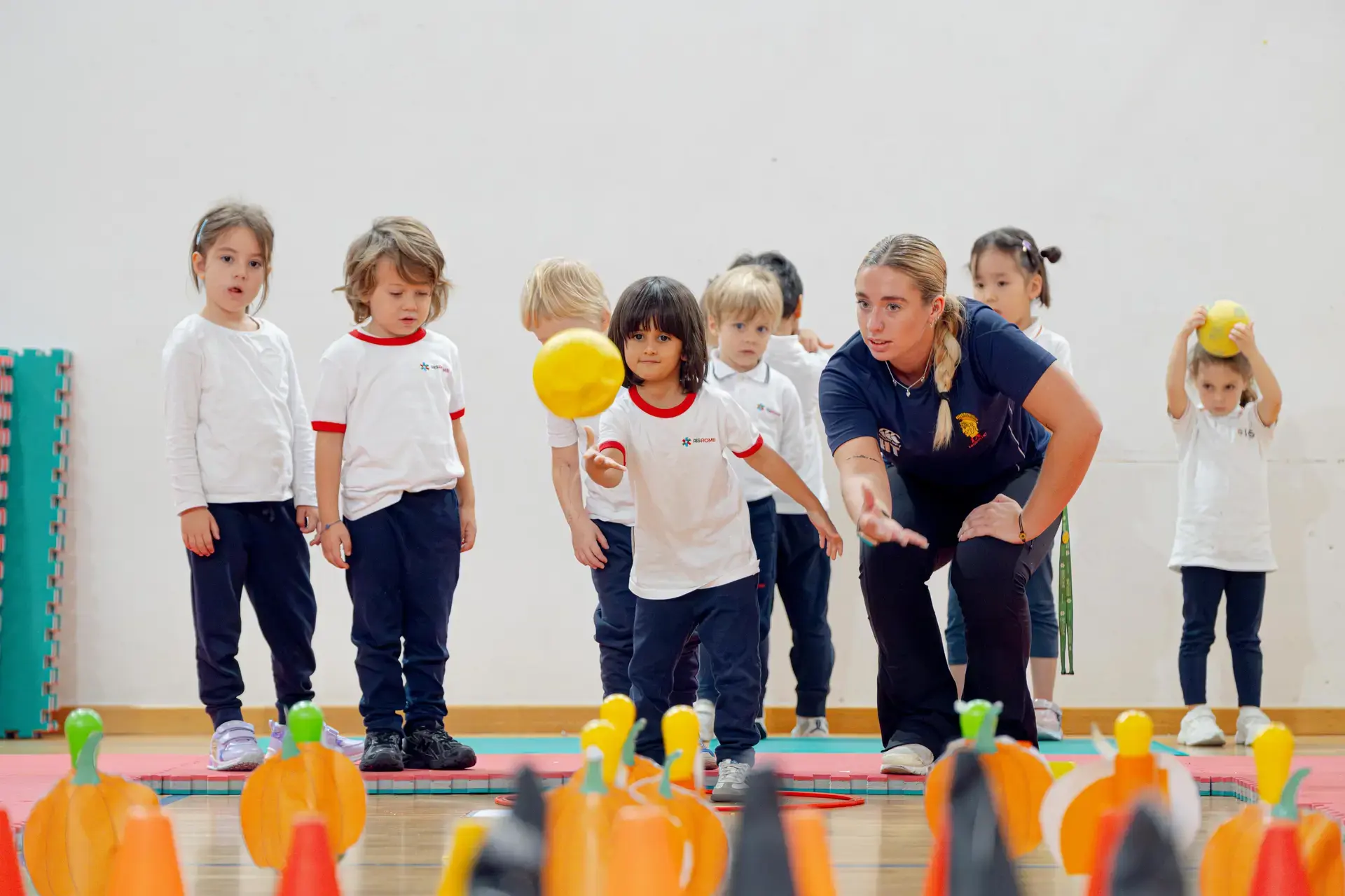 young student tossing a ball with his teacher during a PE class ball-toss game.