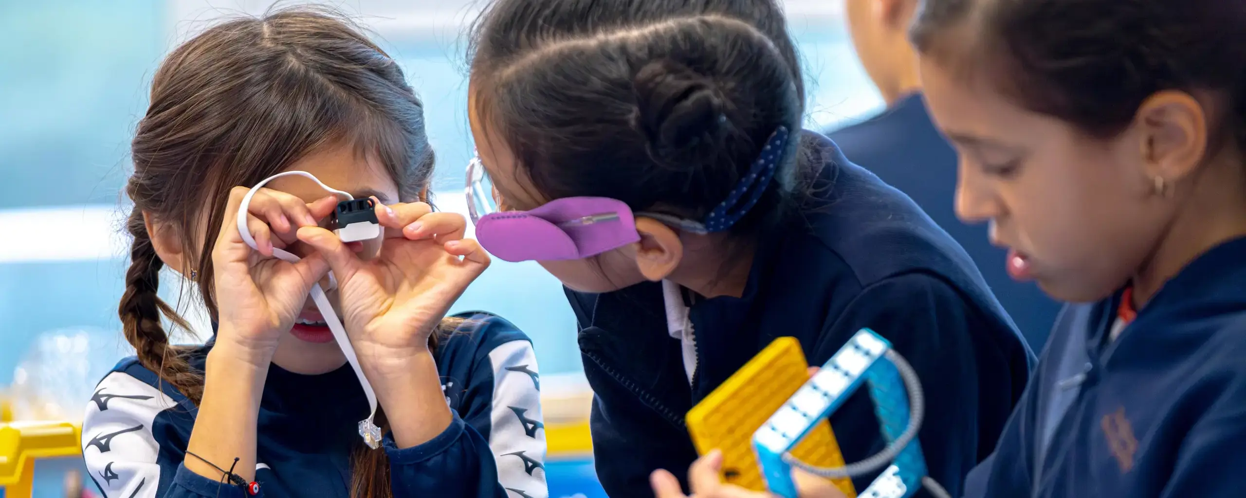 students wearing safety goggles working closely together on a hands-on STEM project.