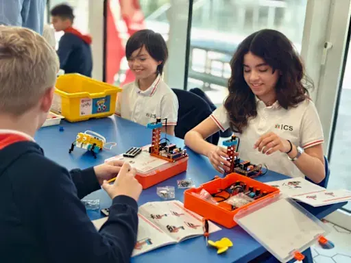 students building robotics kits together at a classroom table.