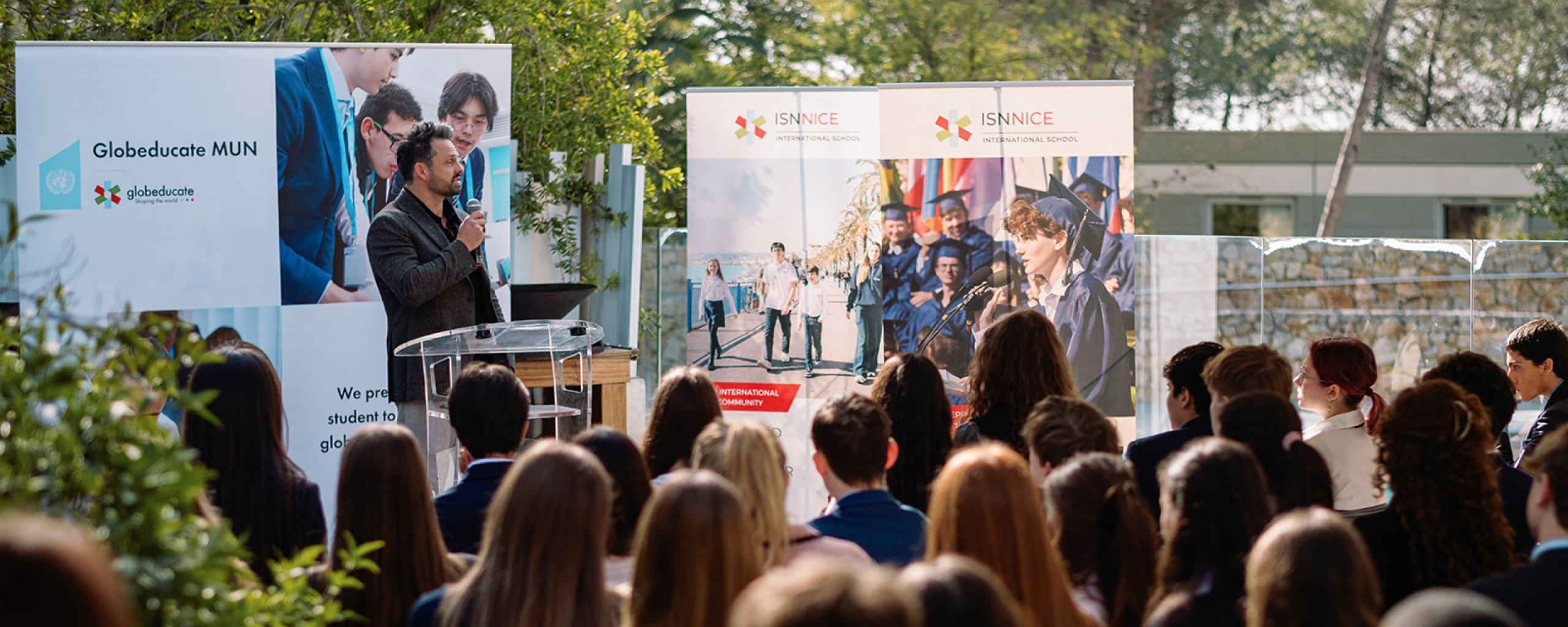 speaker addressing students outdoors at a podium during a Globeducate Model United Nations even