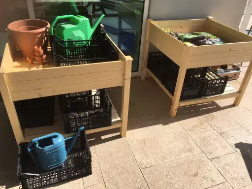 raised wooden garden planter boxes with watering cans and crates on the school rooftop.