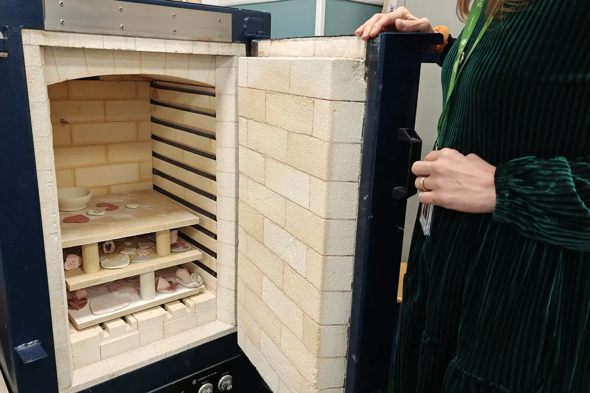 student loading a piece into a kiln in the ceramics studio.