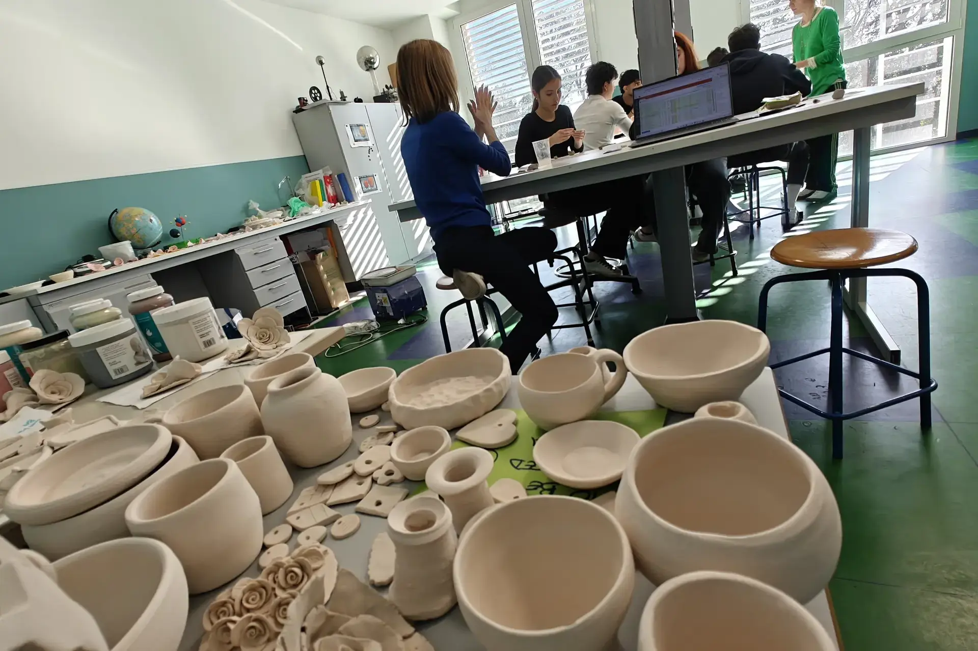 rows of handmade clay pottery displayed in the ceramics studio.