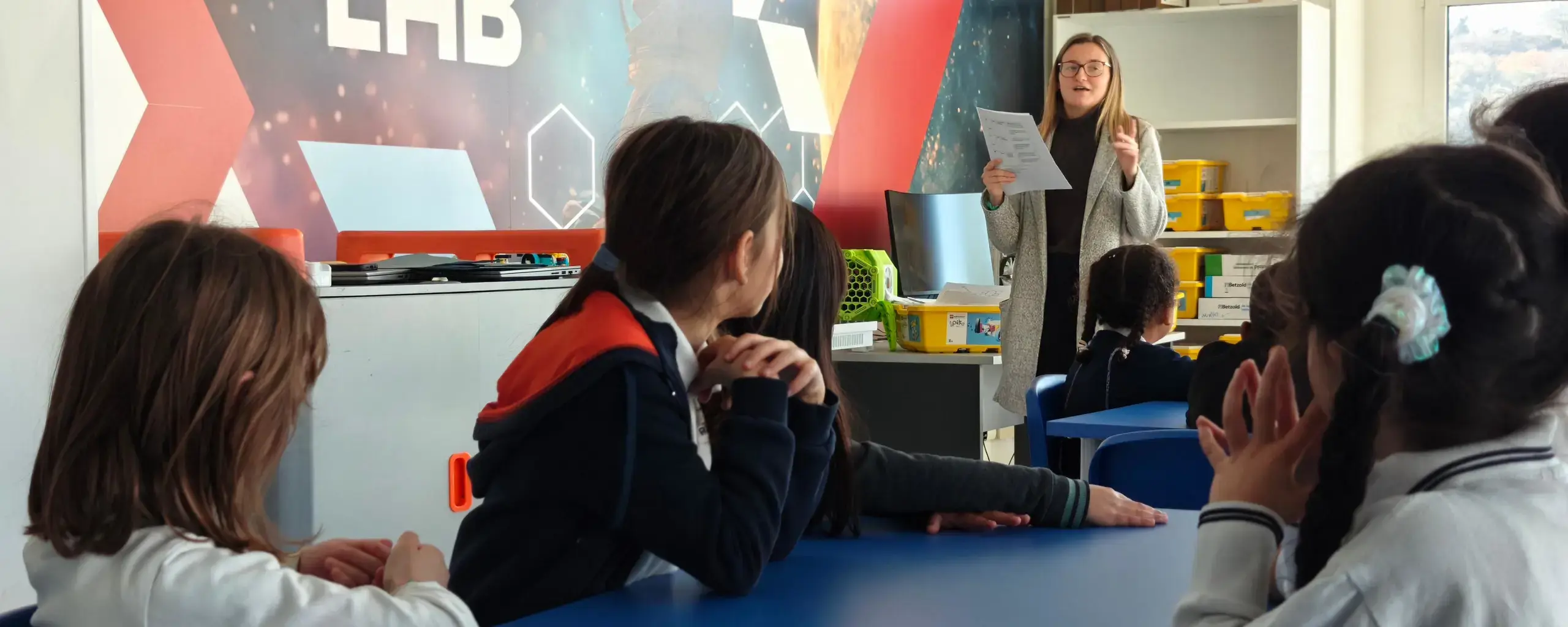 teacher leading a lesson with students seated at tables in the Space Lab classroom