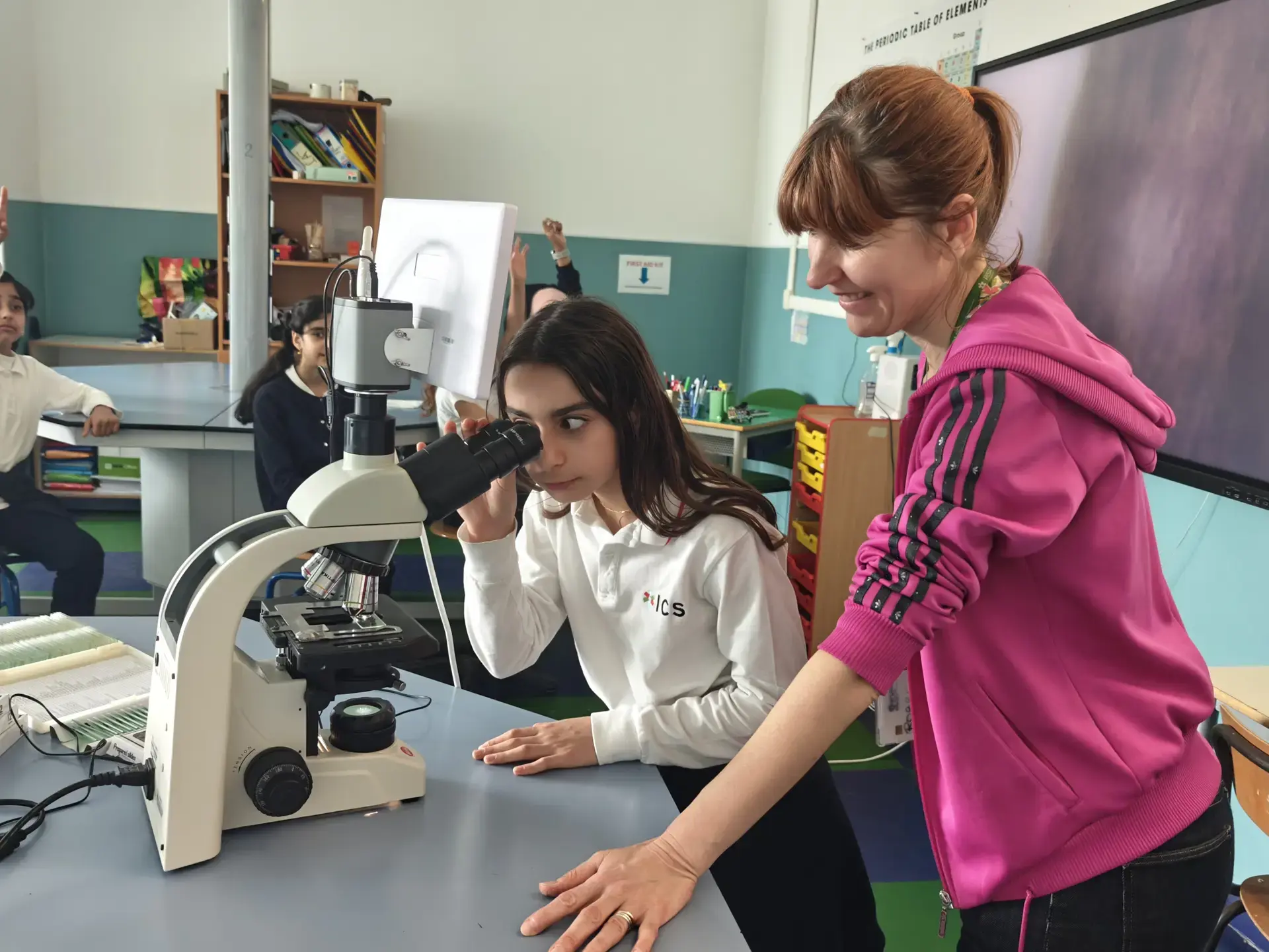 student examining a sample under a microscope in science clas