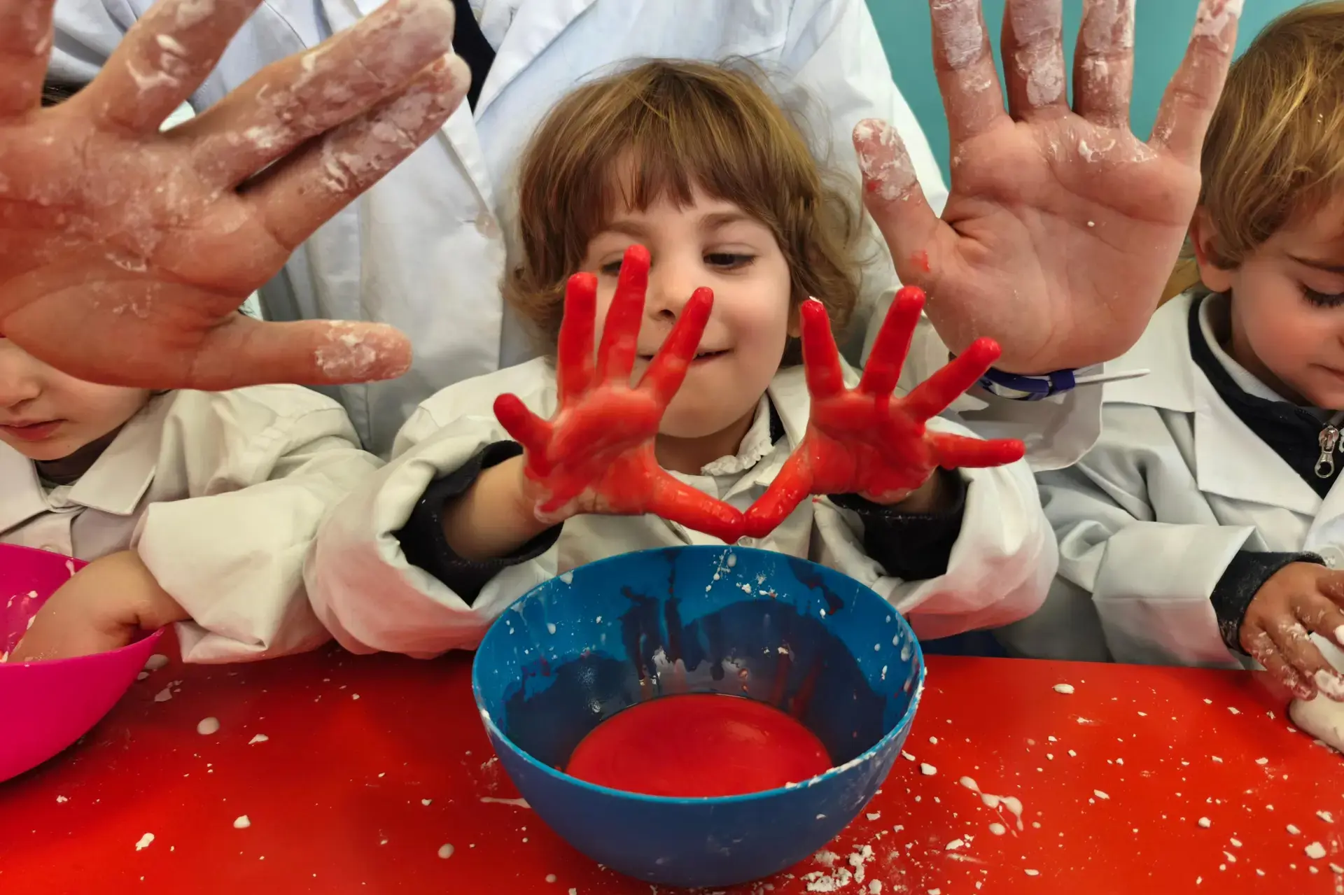 young student showing red-painted hands during a messy sensory art activity