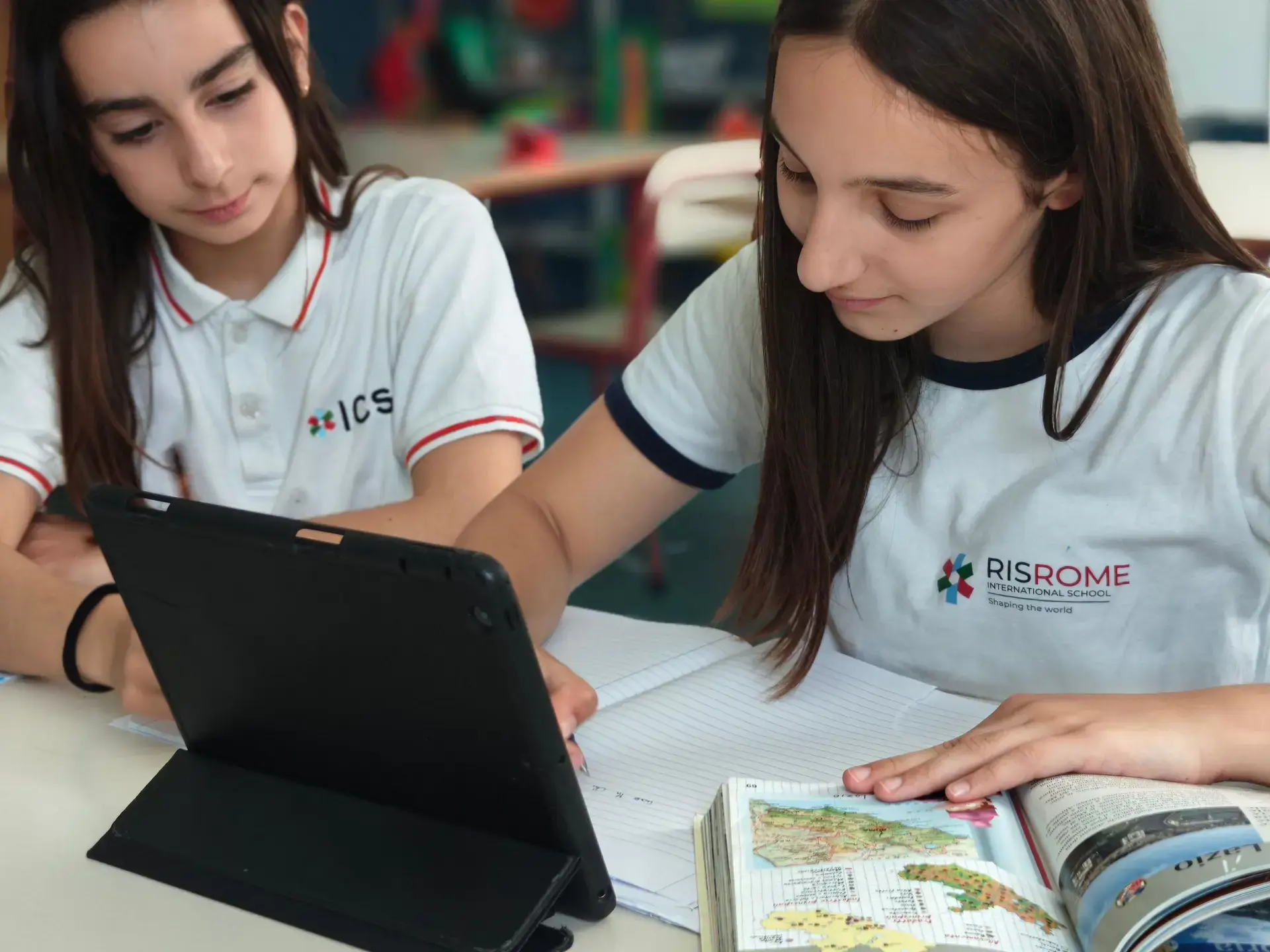 students working together on a tablet and notebook during class