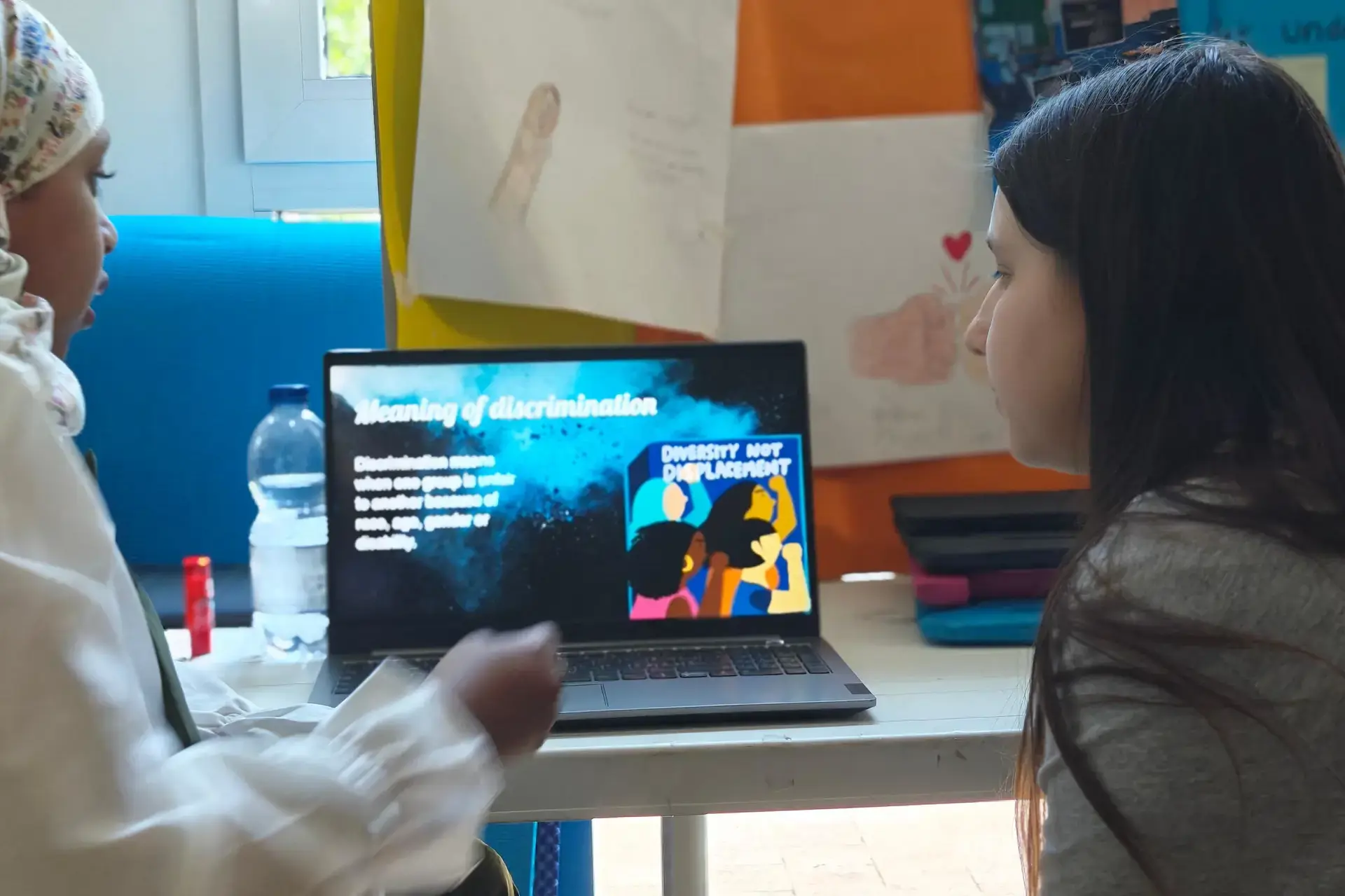 students looking at a laptop screen displaying a colorful design.