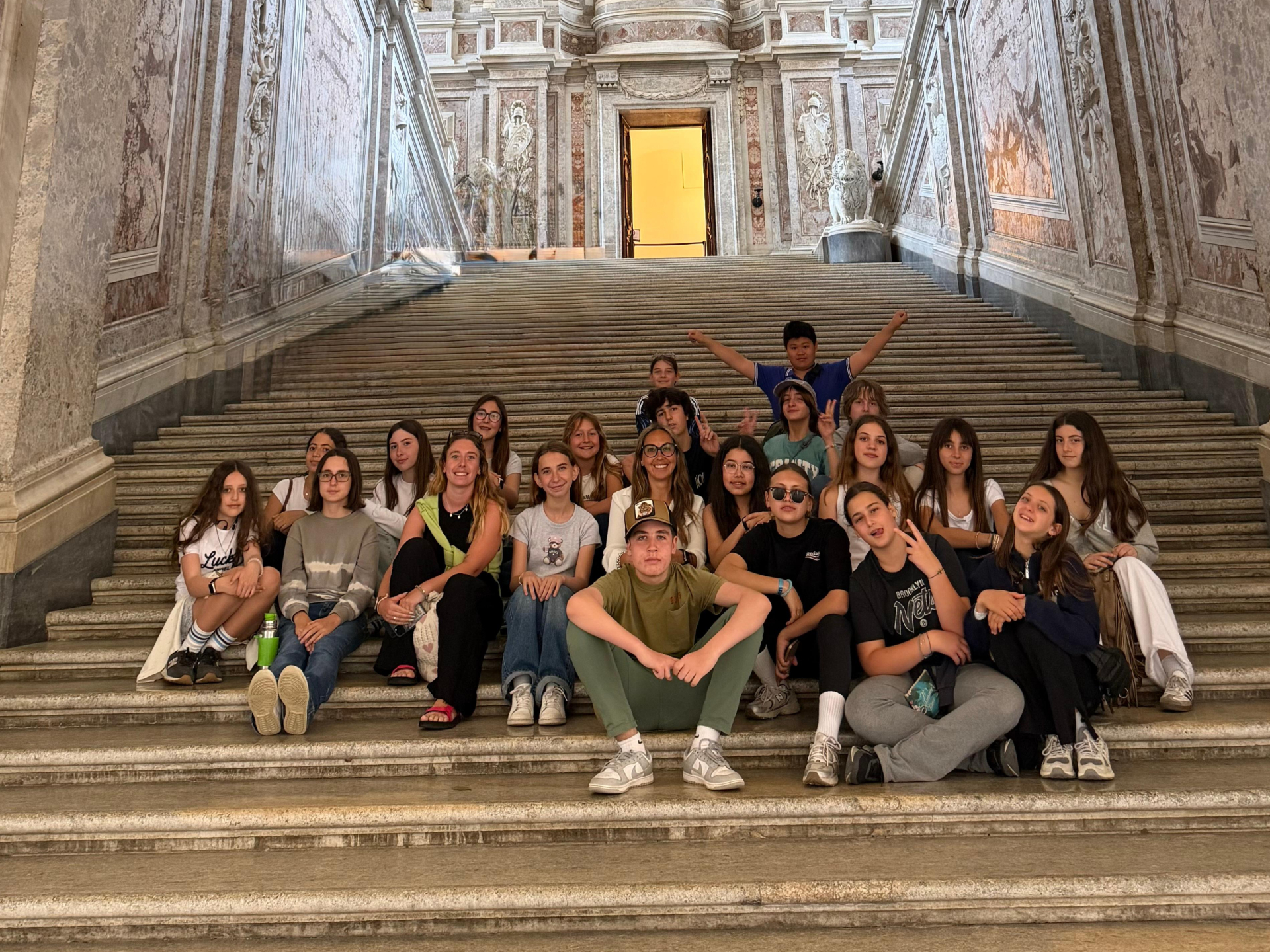 students posing on a grand staircase during a school trip