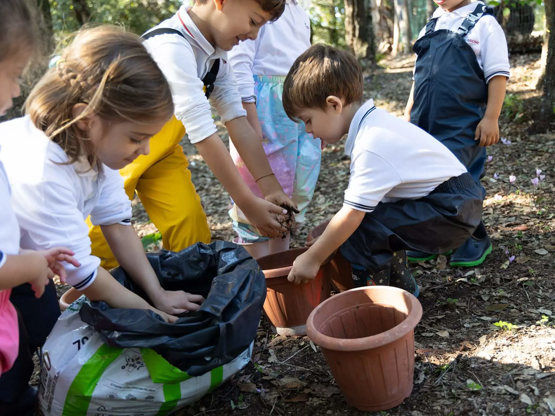 RIS students filling plant pots with soil in a garden