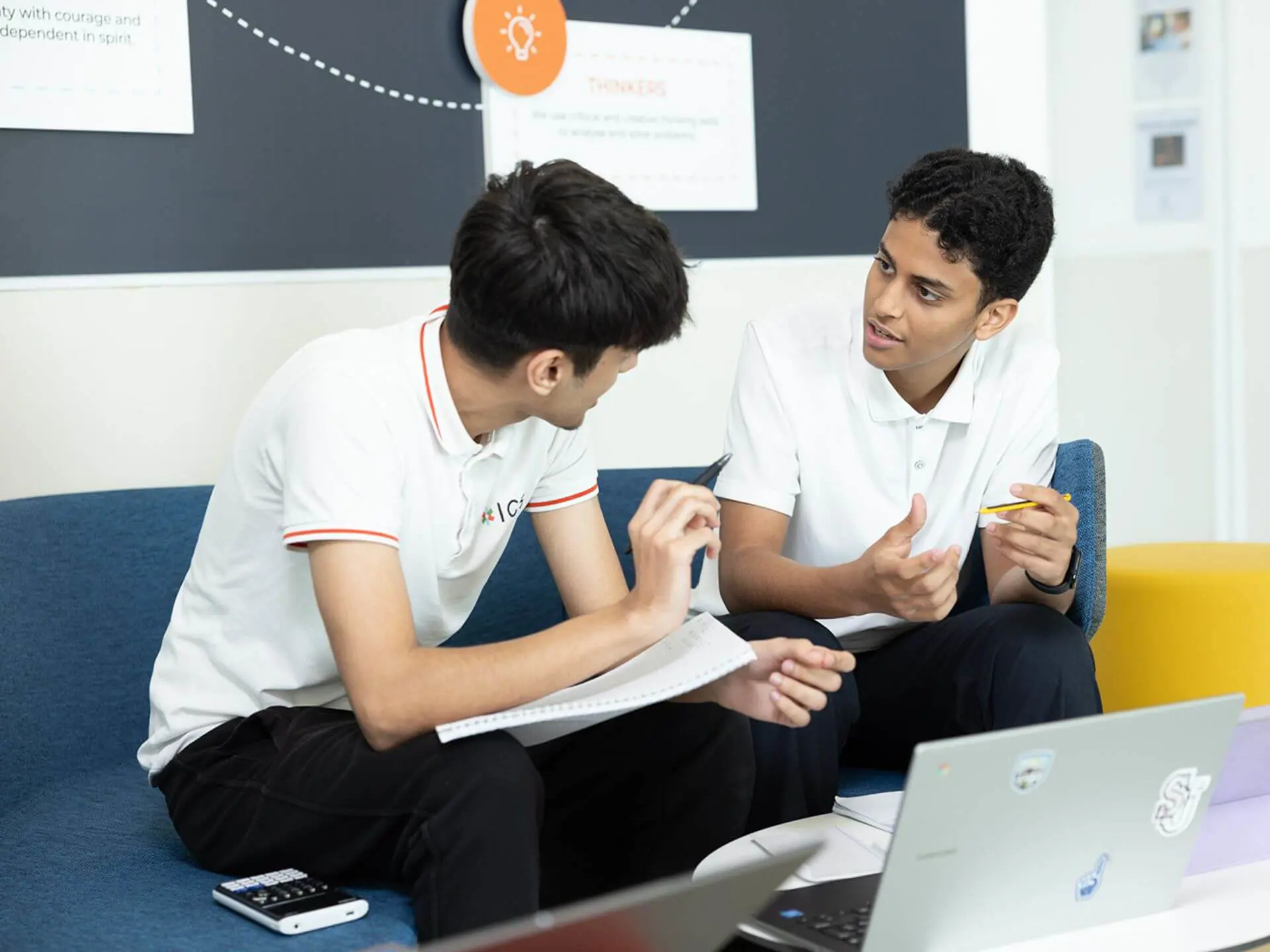 RIS students with notebooks and a laptop discuss classwork