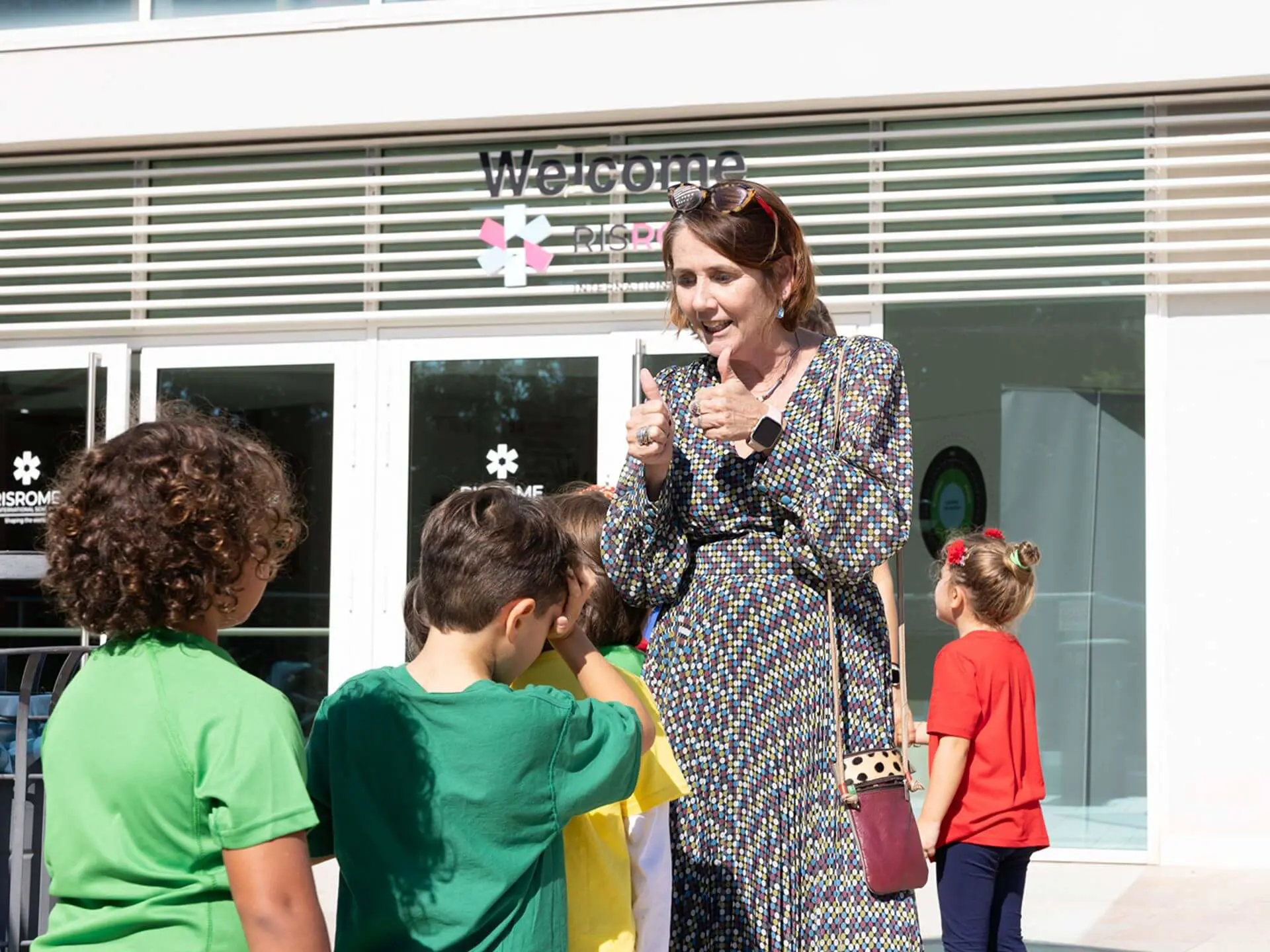 RIS teacher giving thumbs up to a line of students in the playground