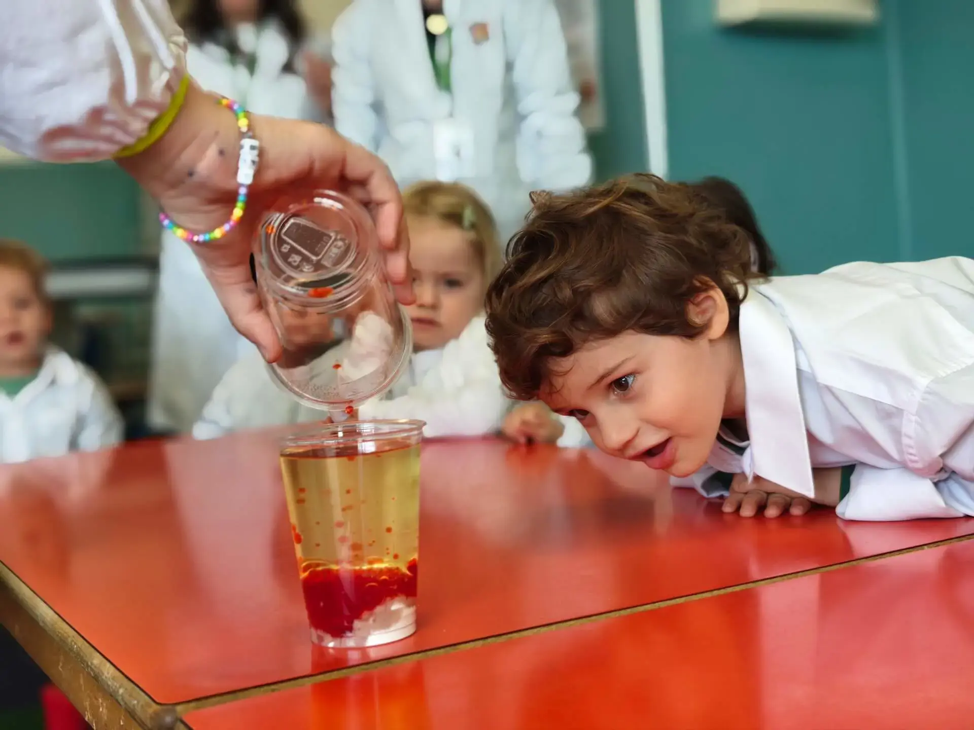 young student watching a science experiment with colored liquid in a classroom