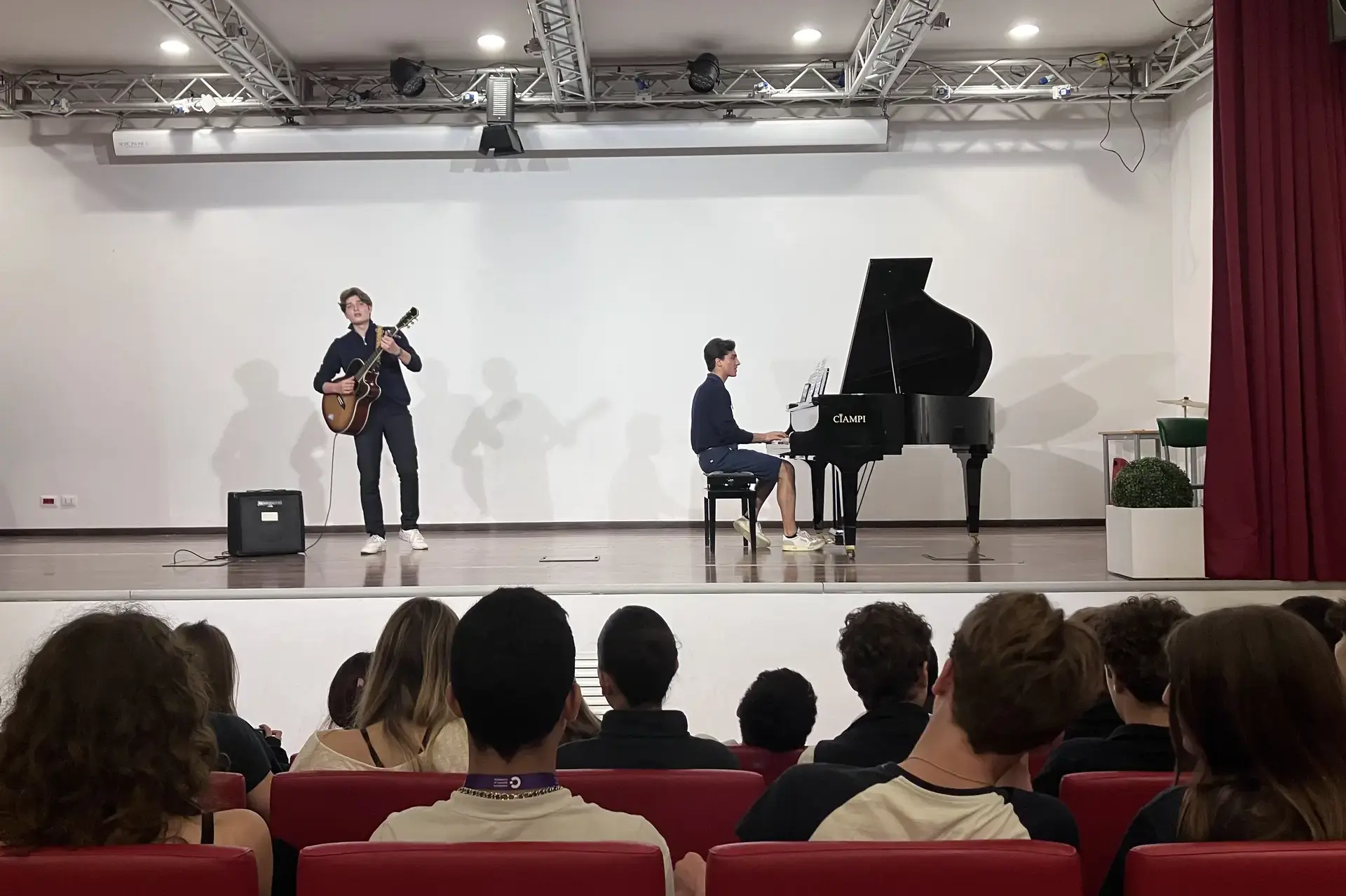 students performing music on stage in front of a seated audience.