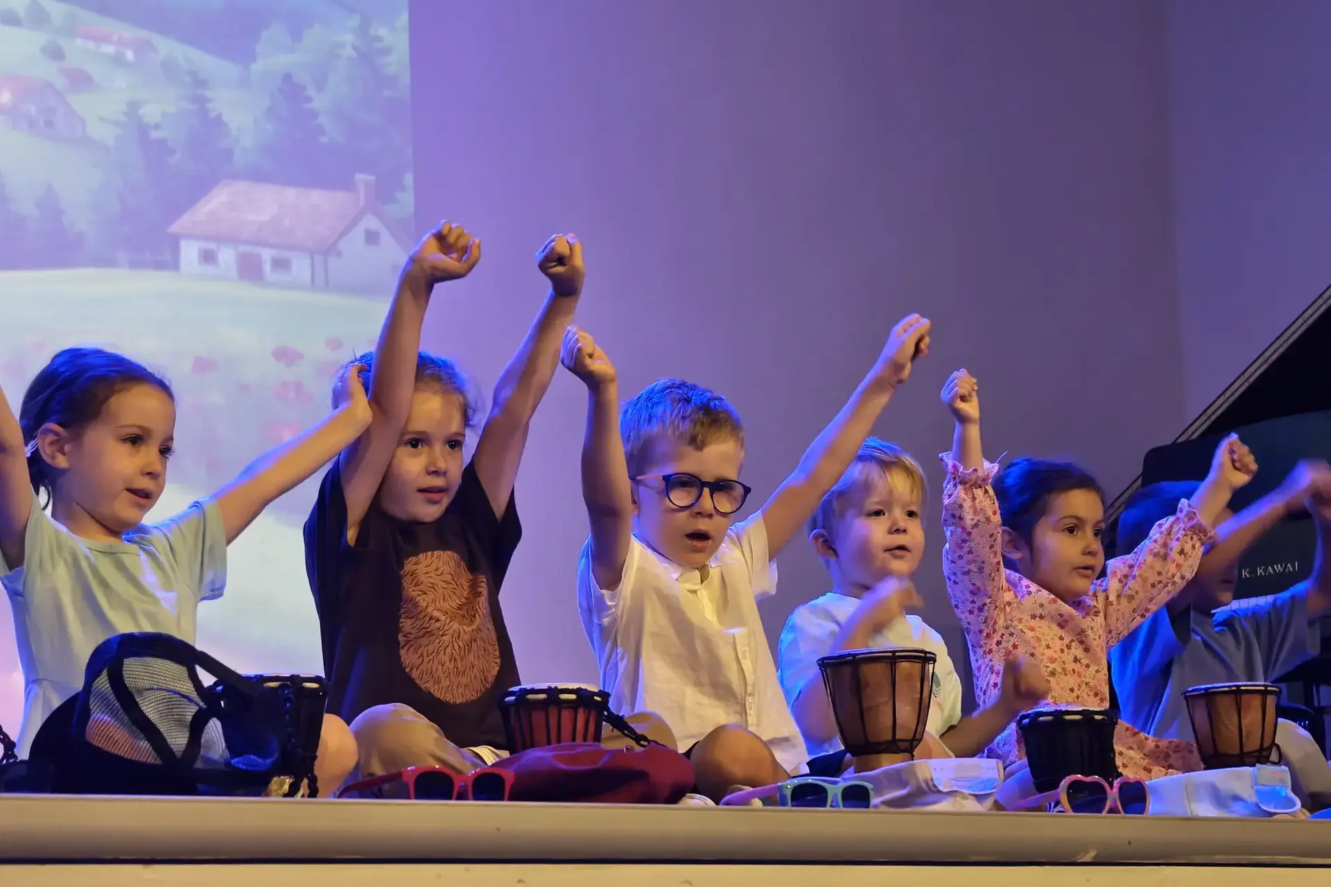 young students playing drums together on stage during a performance.