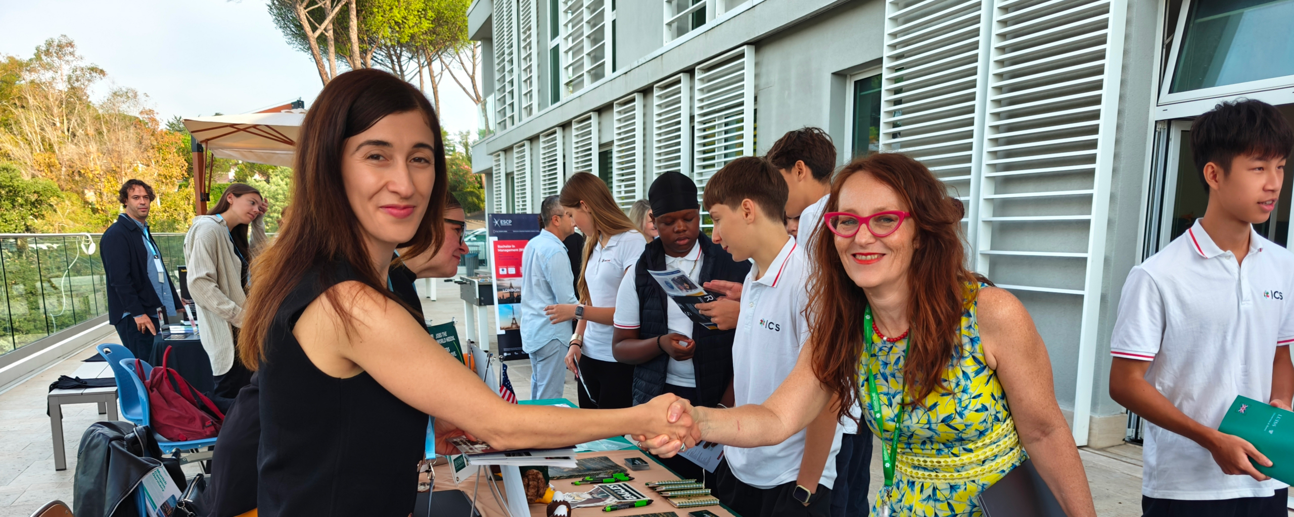 teachers shaking hands with a university representative at a school university fair