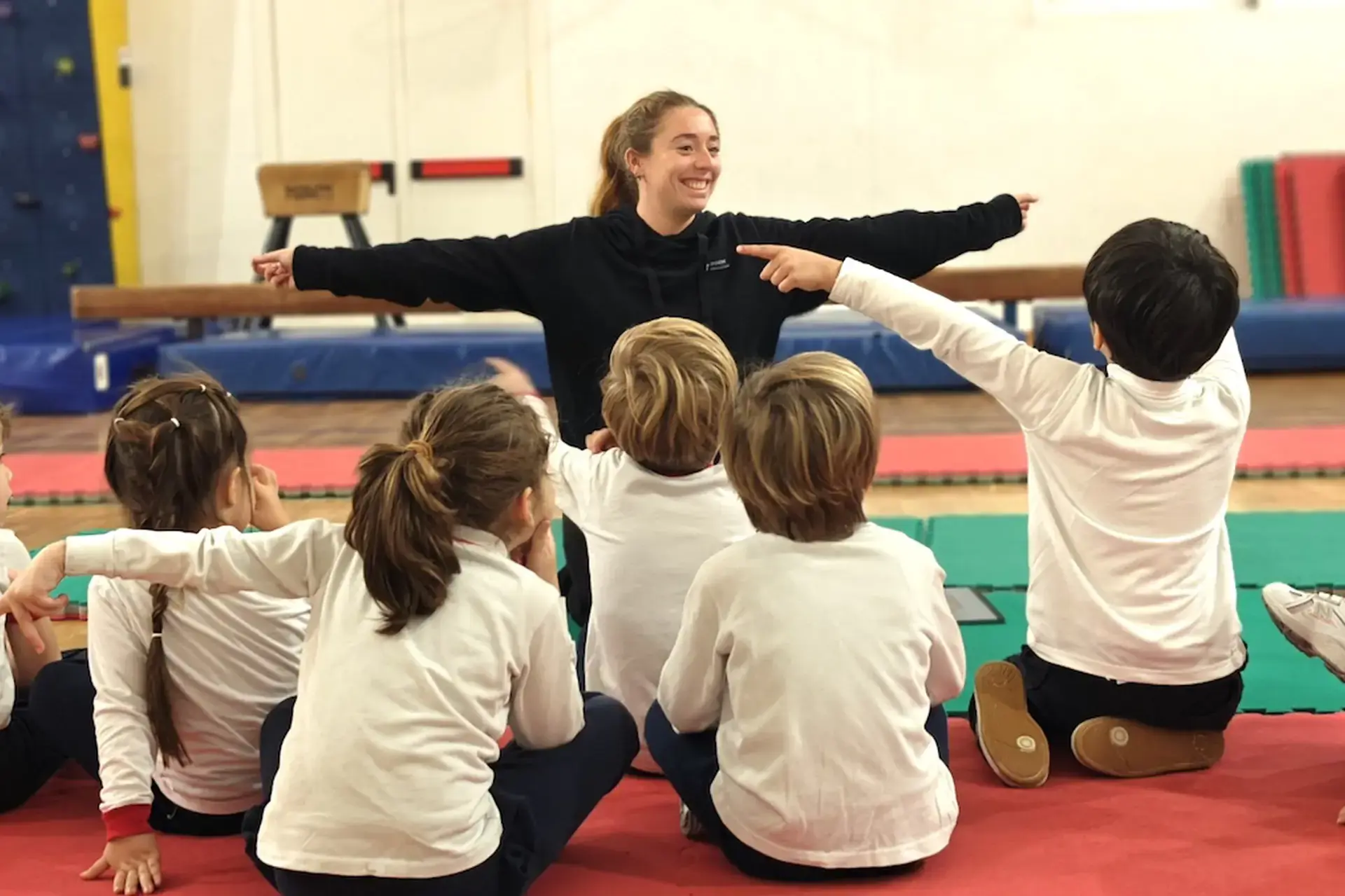 students sitting on a gym mat during a physical education class