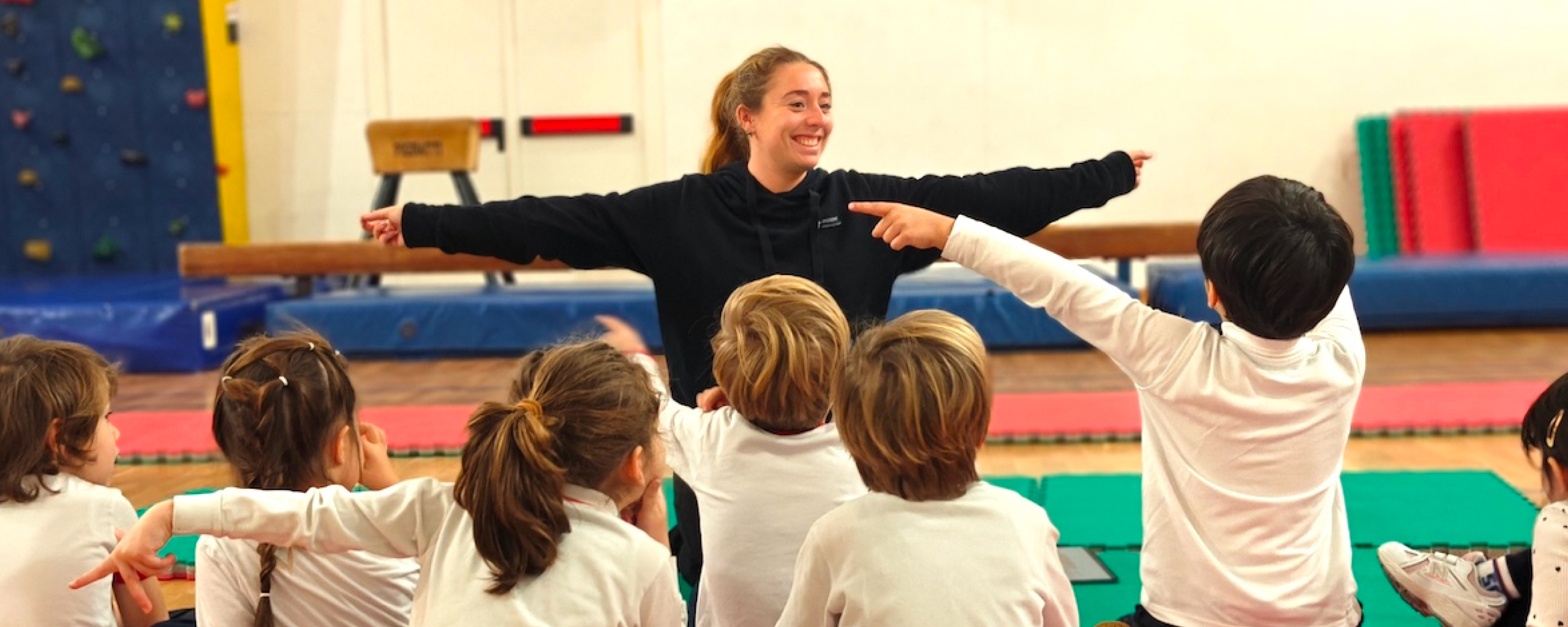 pe teacher demonstrating an exercise with young students in the gym