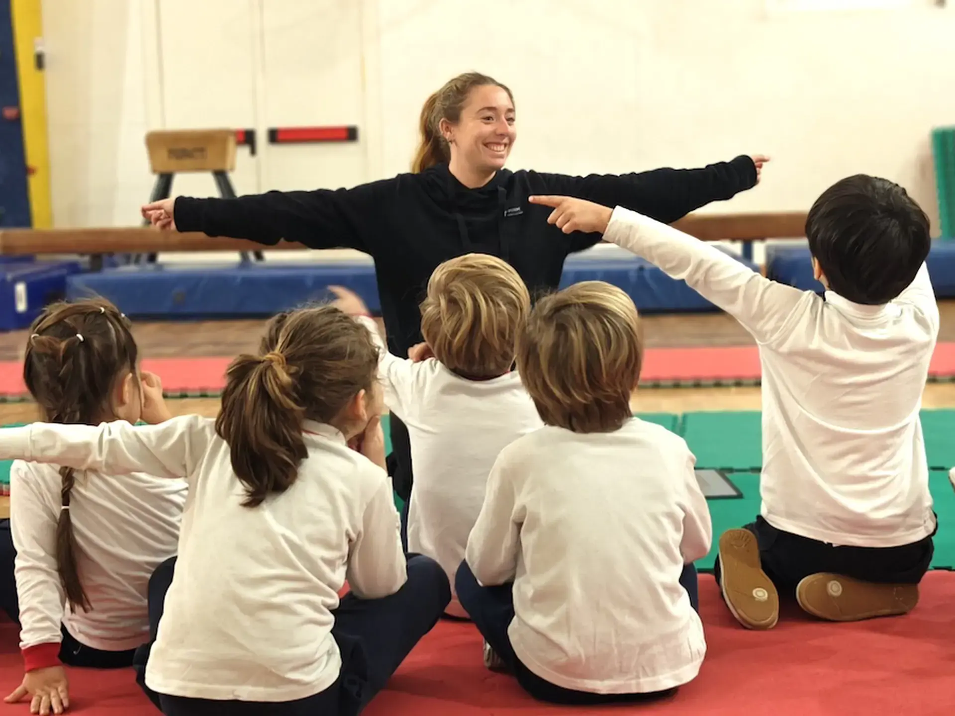 pe teacher demonstrating an exercise with young students in the gym
